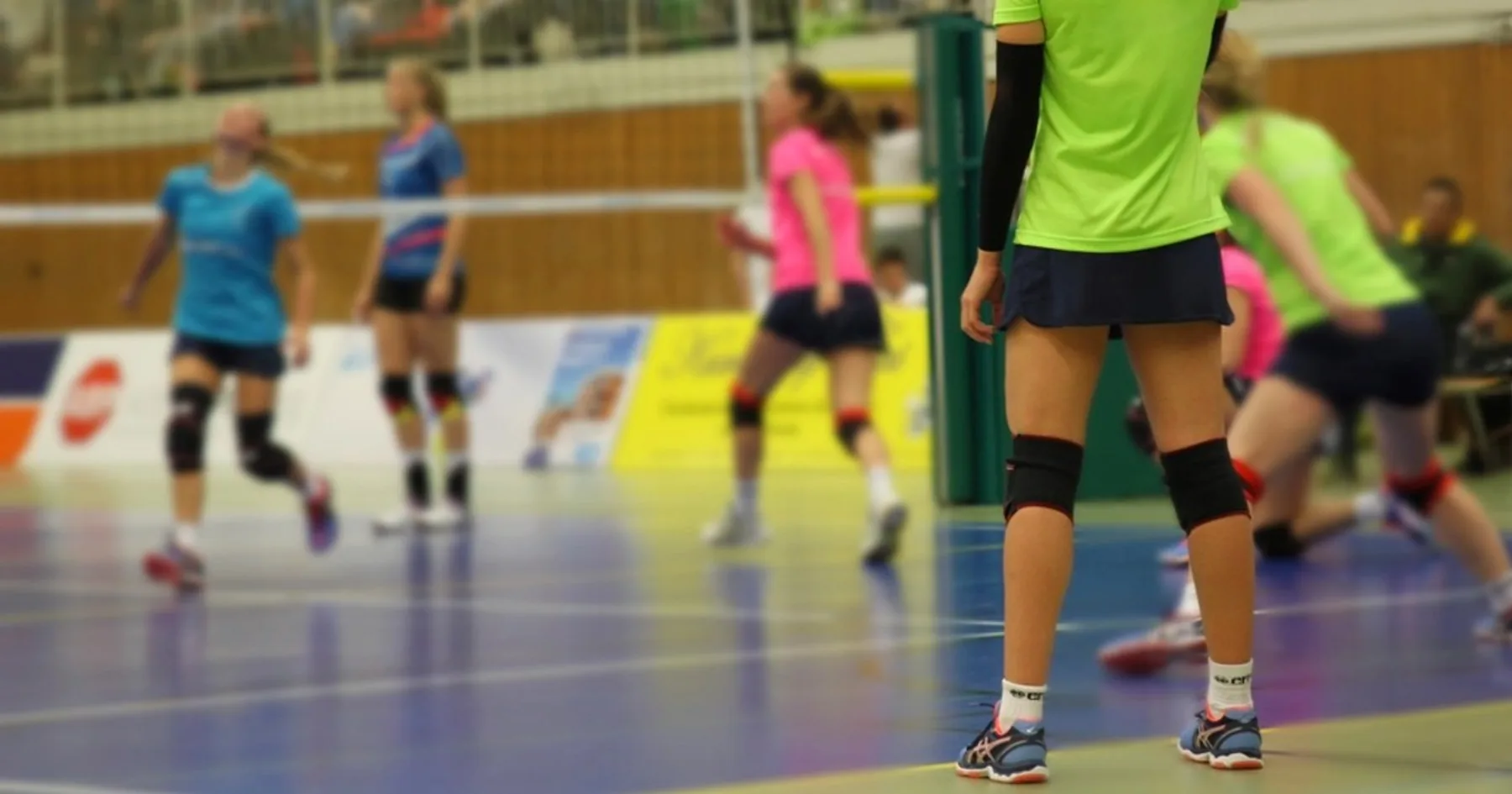 Jogadoras de vôlei em ação durante partida em quadra coberta